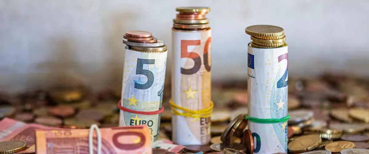 Opgerolde eurobiljetten en munten op tafel